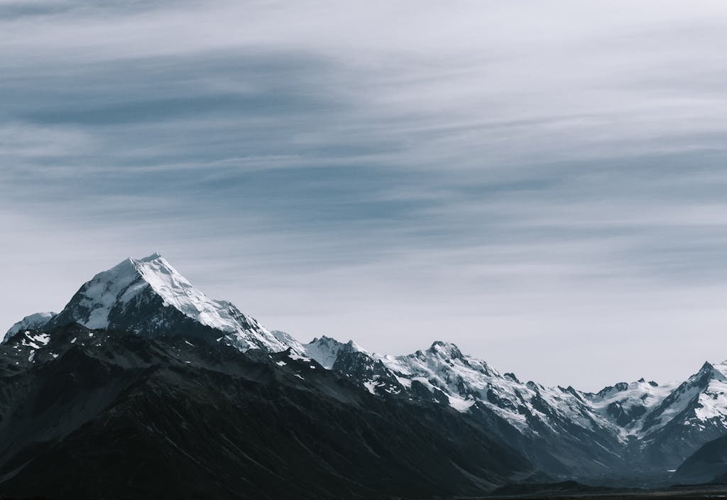 Breathtaking view of snow-capped mountain peaks under a cloudy sky.