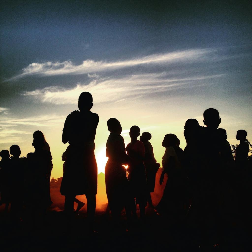 Silhouettes of a group of people against a vibrant sunset sky in Lilongwe, Malawi.